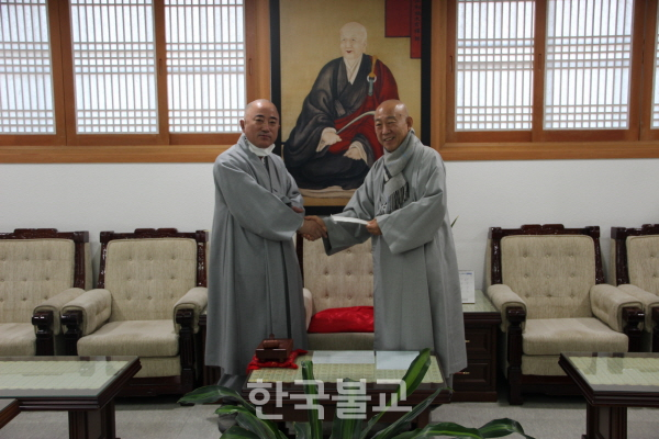서울북부교구 종무원장 육화 스님이 총무원장 호명 스님에게 종단발전성금을 전달하고 있다.