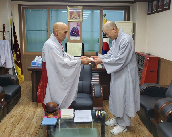 관암사 주지 영범 스님(사진 오른쪽)이 종무원장 법운 스님에게 태고사 인수 성금을 전달하고 있다.