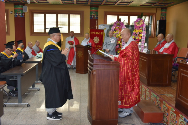 종립 동방불교대학 이사장이자 총무원장 호명 스님이 종정권한대행 이름으로 졸업생 대표 법천 스님에게 법계증을 수여하고 있다.