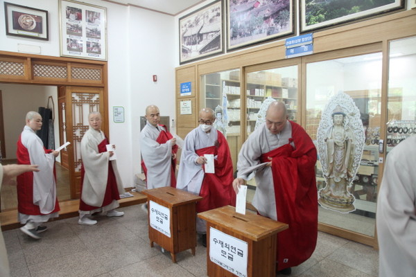 청련사 대중 스님들이 차례로 나서 수재의연금을 내고 있다.