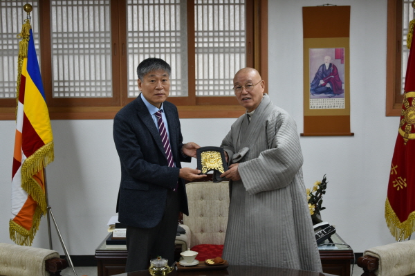총무원장 상진 스님이 박찬영 부산시장 정무특보에게 귀와 문양의 장식품을 선물하고 있다.