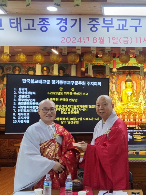 중앙종회의원 월주 스님이 종무원장 지허 스님에게 성금을 전달하고 있다.