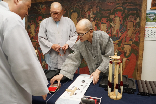 서예지도를 맡은 운봉 스님이 '초지일관' 한자를 족자에 적고 낙관을 찍고 있다.