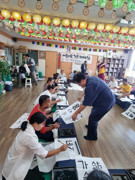 한국예술문화원 매곡 조윤곤 이사장이 네팔 이주민 불자들에게 한글 서예 지도를 하고 있다.