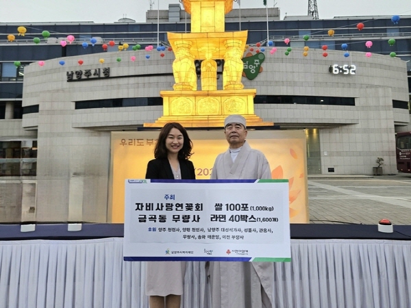 자비사랑연꽃회 회장 탄허 스님이 남양주 시청 앞 봉축 점등식에서 신영미 동부희망케어센터장에게 백미와 라면을 전달하고 있다.