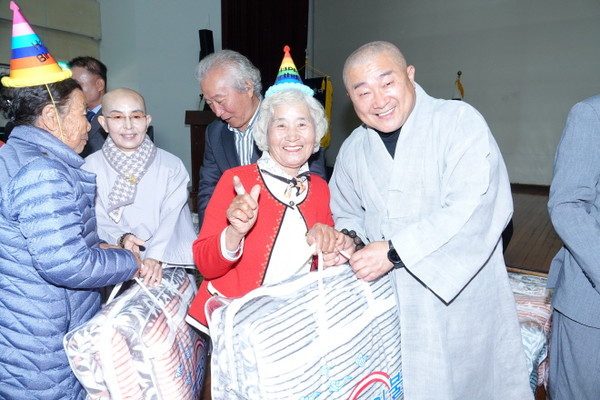 마이산탑사 주지 진성 스님이 어르신들에게 생일선물로 이불을 전달하고 있다.
